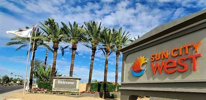 Sun City West entry sign with palm trees and blue sky in Sun City West, Arizona