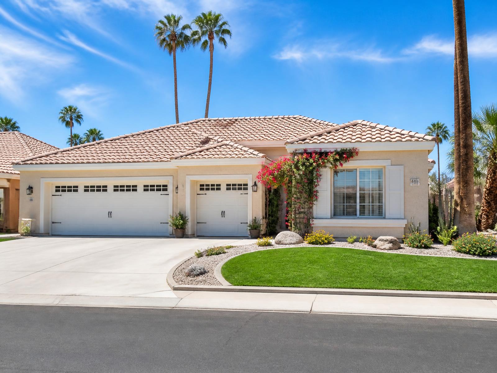 Sunlit single-story Arizona active adult home with palms, bougainvillea and a bright blue sky